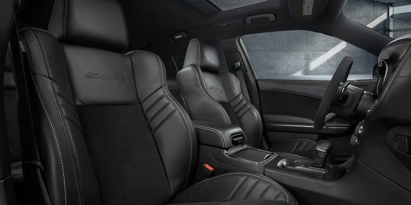 Black leather car interior with SRT logo on seats, white stitching, center console, and steering wheel.