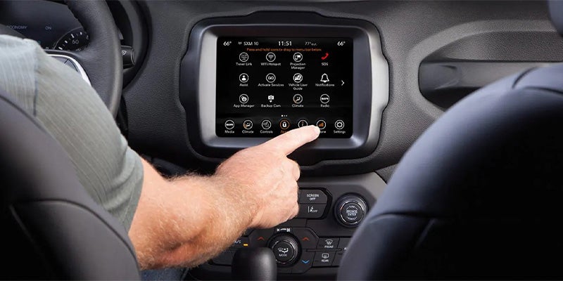 Hand touching touchscreen infotainment screen in Jeep SUV