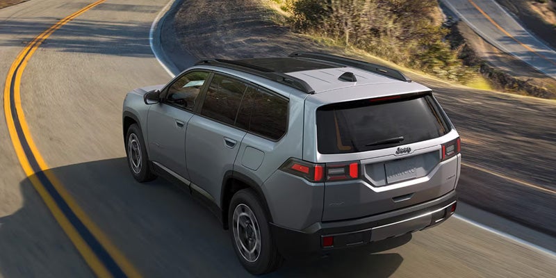 Rear side view of Jeep SUV driving on road