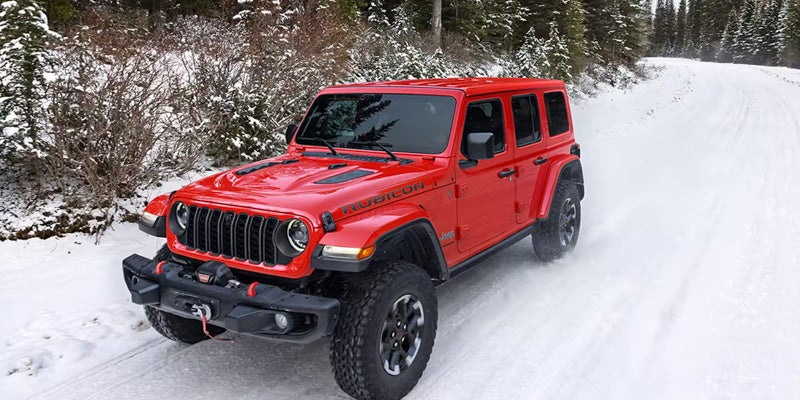 Front side view of Jeep Wrangler driving on snow