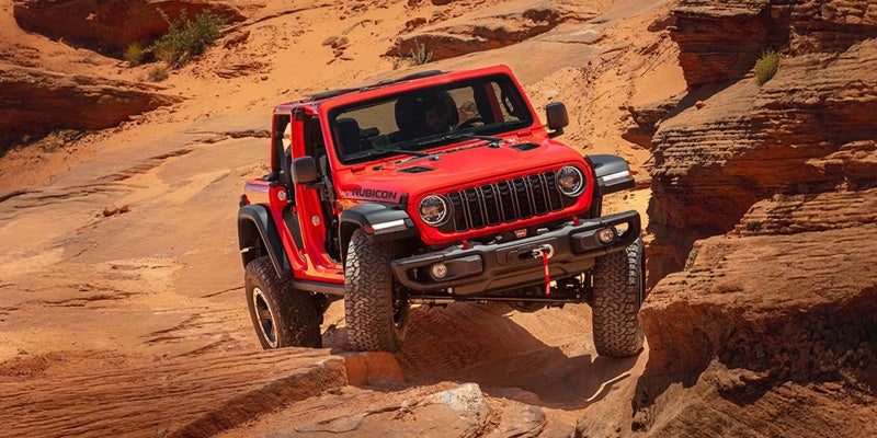 Front side view of Jeep Wrangler driving on rocks