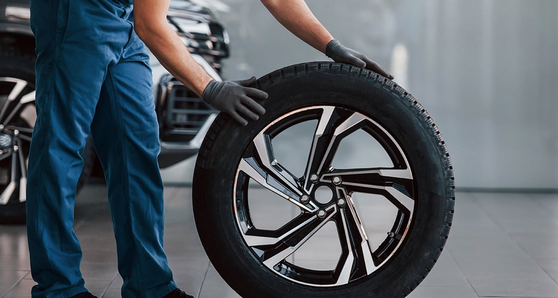 Mechanic rolling new tire in service bay